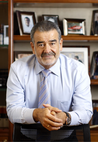 Andronico Luksic, hands folded, looking calmly at camera